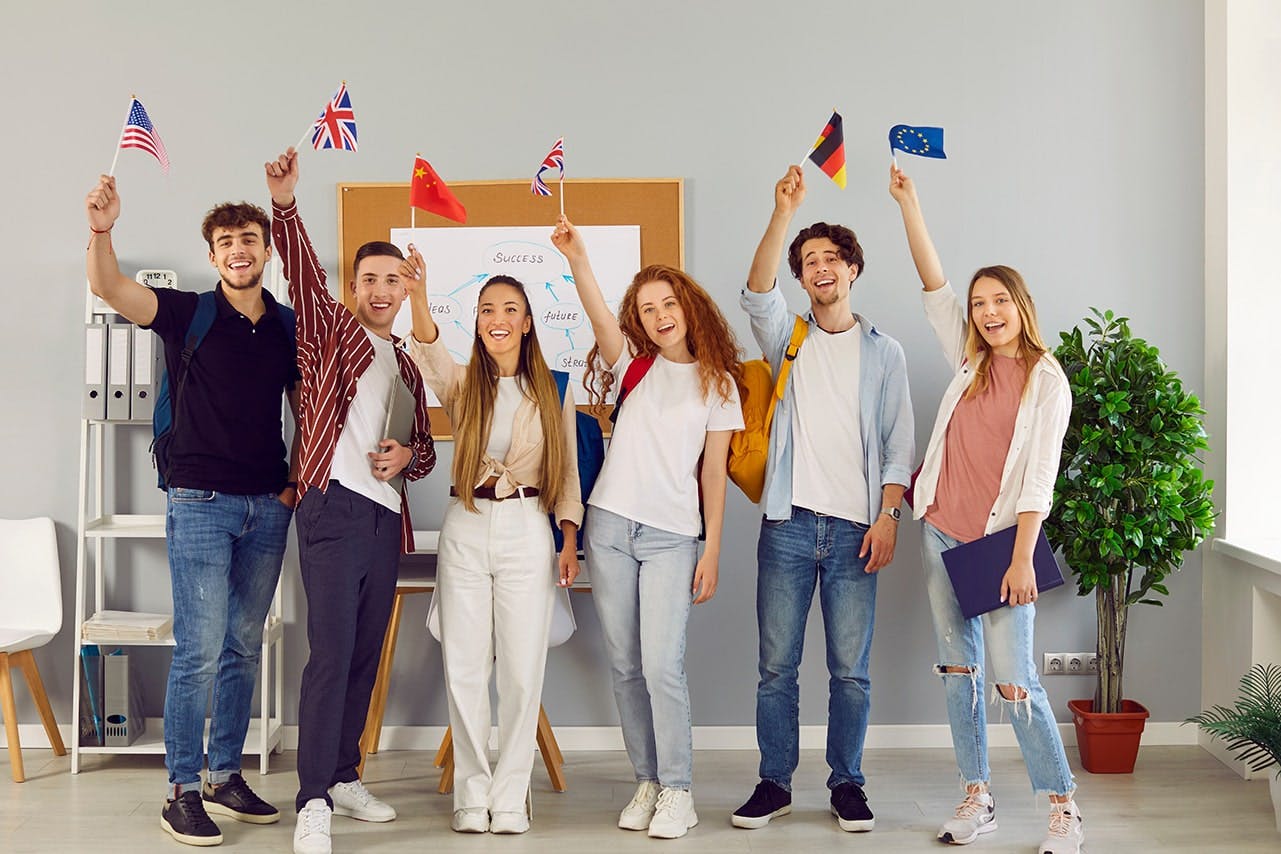 Young adults holding up flags of different countries from around the world